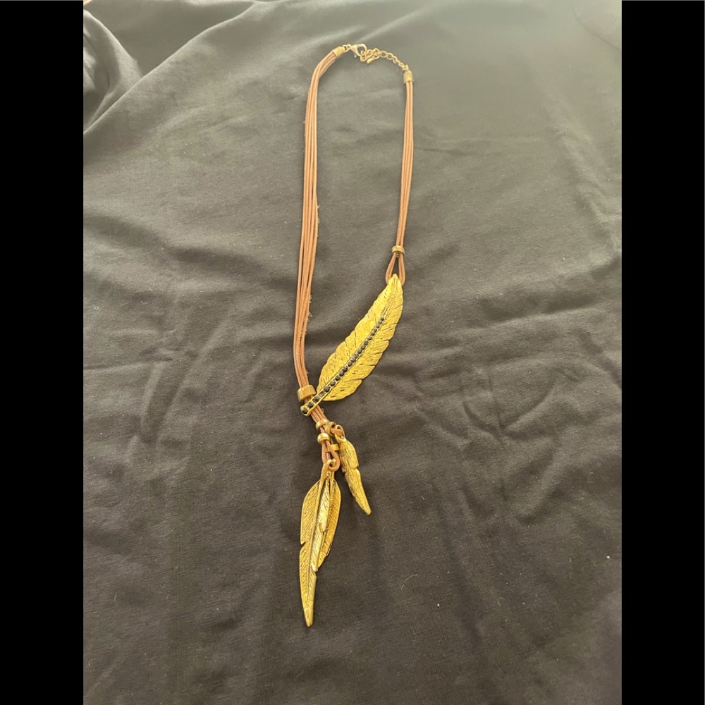 Hold feather on brown leather necklace.